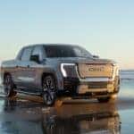 2025 GMC Sierra EV Denali in gray driving on a seaside beach