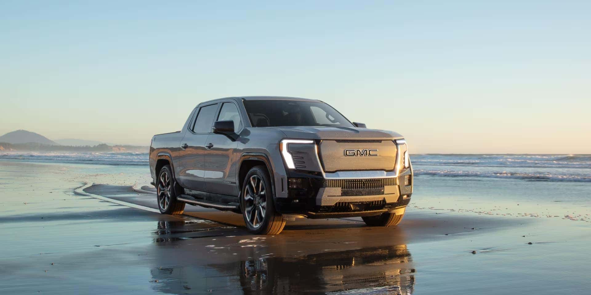 2025 GMC Sierra EV Denali in gray driving on a seaside beach