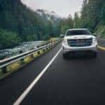 white GMC Sierra driving through pine hills