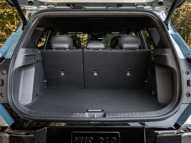 Open trunk of a blue SUV showing ample cargo space. The rear seats are up, revealing a clean and spacious interior, conveying functionality and practicality.
