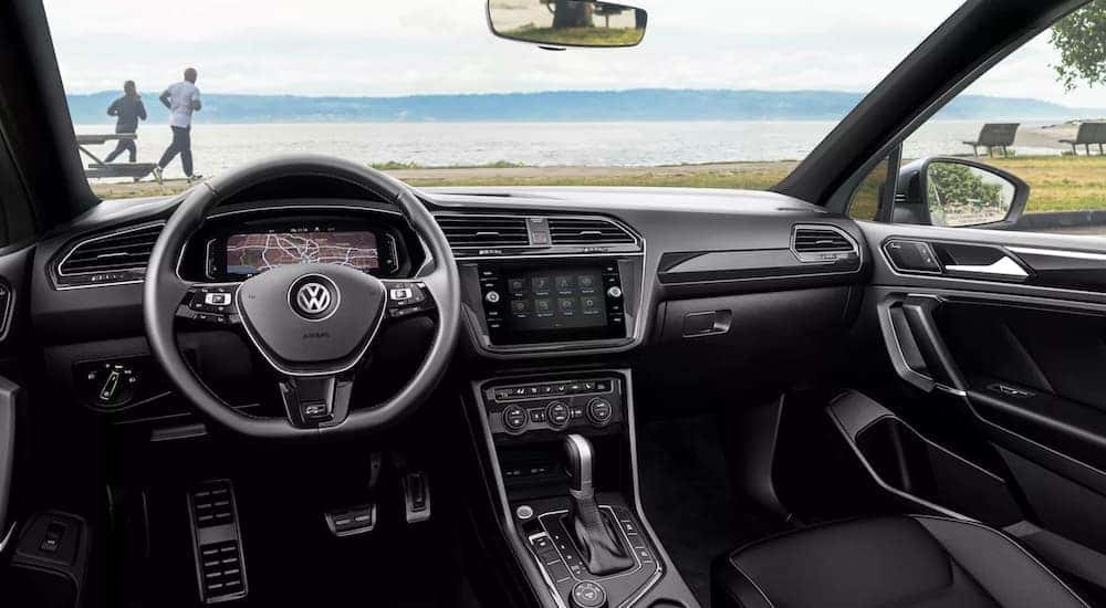 The black interior of a 2021 Volkswagen Tiguan is shown with the a lake through the windshield.