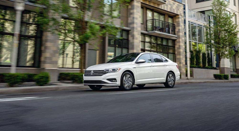 A white 2021 Volkswagen Jetta SEL Premium is shown driving down a city street.