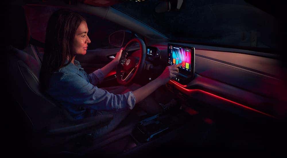 A woman is choosing interior color on the infotainment screen in a 2021 Volkswagen ID.4.