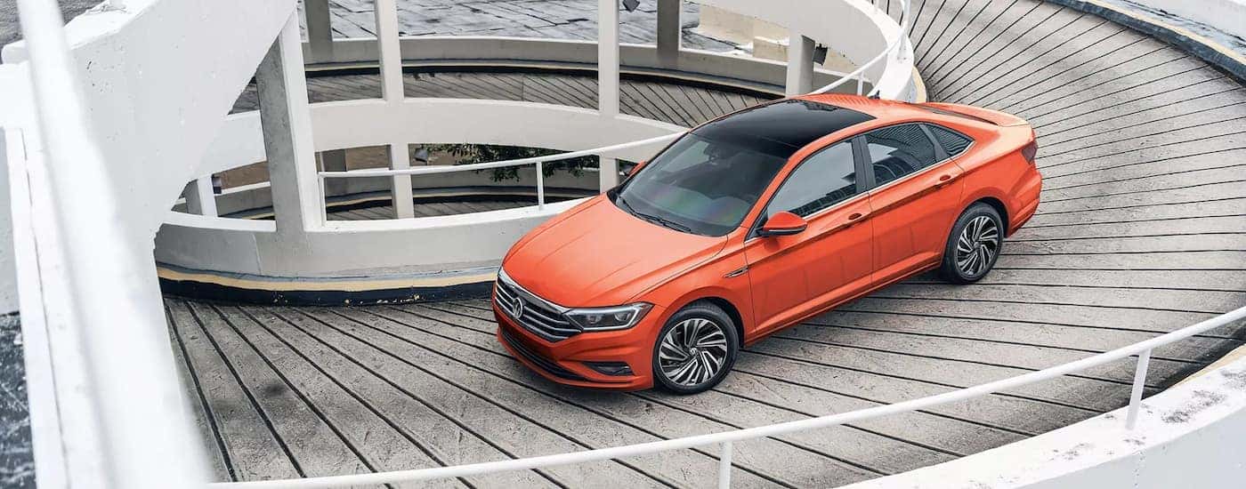 An orange 2021 Volkswagen Jetta is shown leaving a parking garage after visiting a Bellevue VW dealership.
