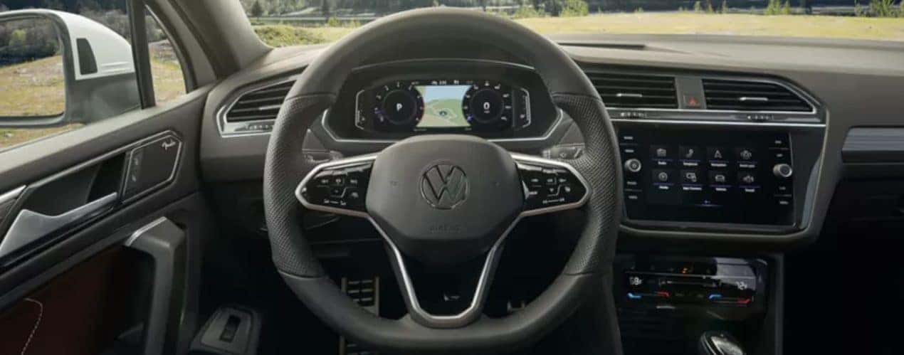 The black interior of a 2022 Volkswagen Tiguan SE shows the steering wheel and infotainment screen after winning a 2022 Volkswagen Tiguan vs 2022 Subaru Forester comparison.
