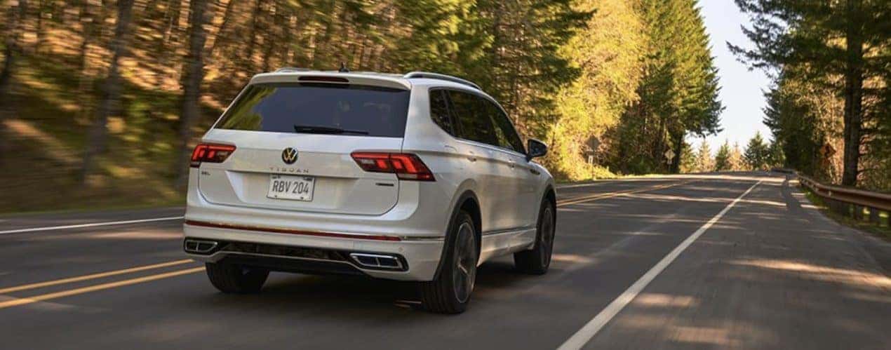 A white 2022 Volkswagen Tiguan SE is shown from the rear driving on an open road.
