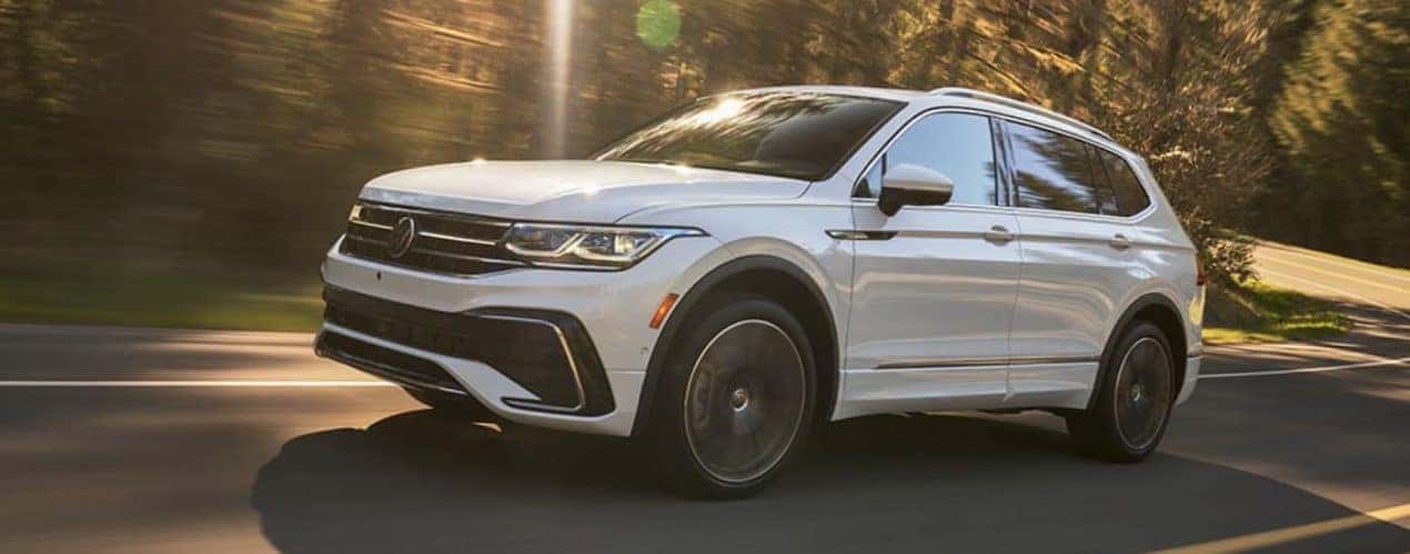 A white 2022 Volkswagen Tiguan SE is shown from the side driving on an open road.