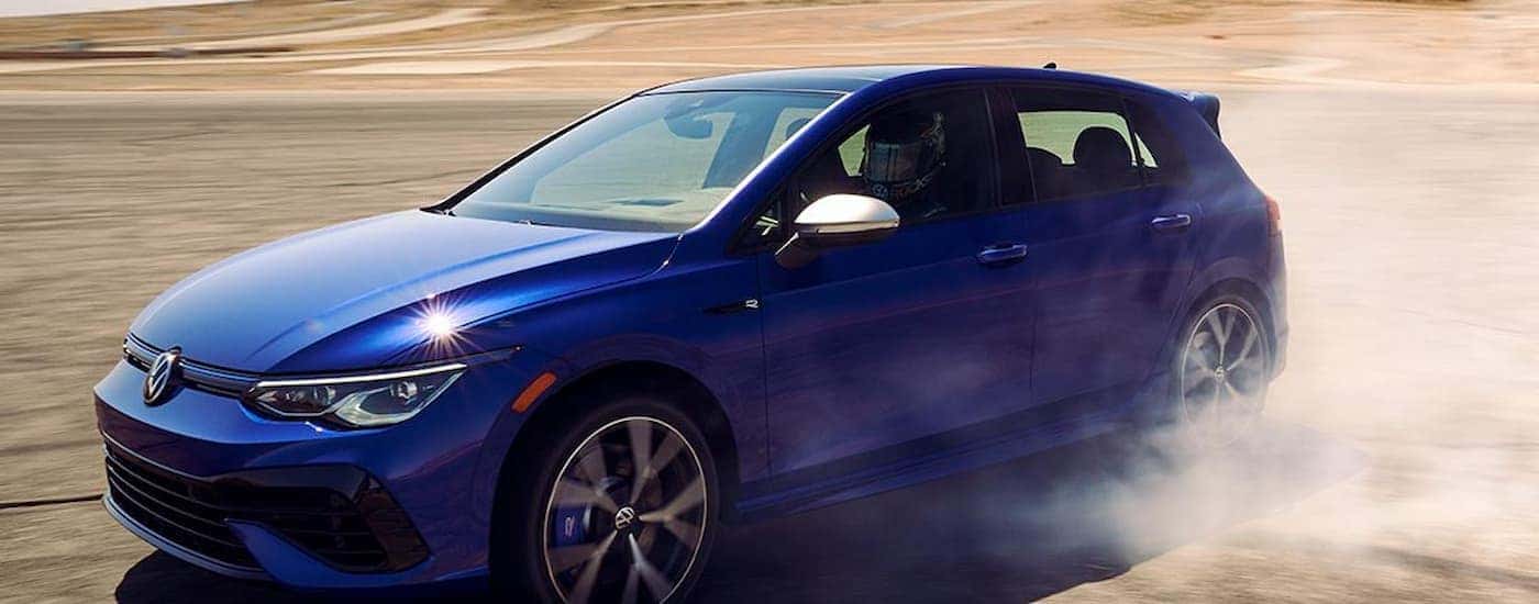 A blue 2022 Volkswagen Golf R is shown speeding on a racetrack.