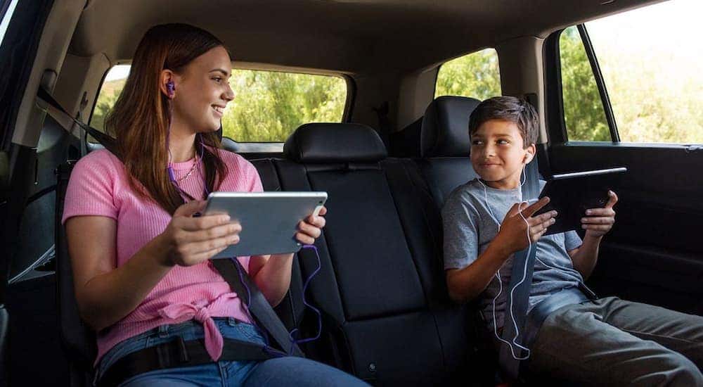 Children are shown in the back seat of a 2022 Volkswagen Tiguan using tablets.