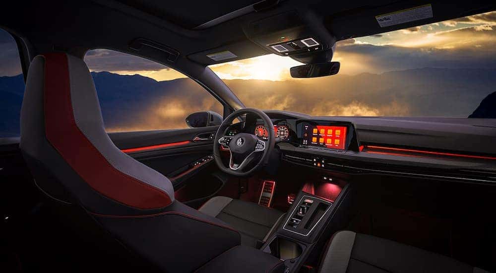The black interior of a 2022 Volkswagen Golf GTI shows the front seats.