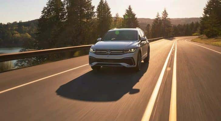 A white 2022 Volkswagen Tiguan is shown driving past a lake after leaving a Seattle VW Tiguan dealer.