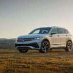A white 2022 Volkswagen Tiguan is shown from the front at an angle while parked in a field after leaving a Tacoma Volkswagen dealer.