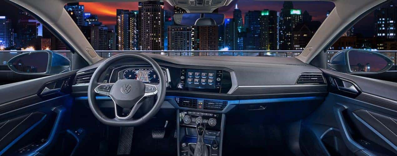 The grey interior of a 2022 Volkswagen Jetta SEL shows the steering wheel and infotainment screen.