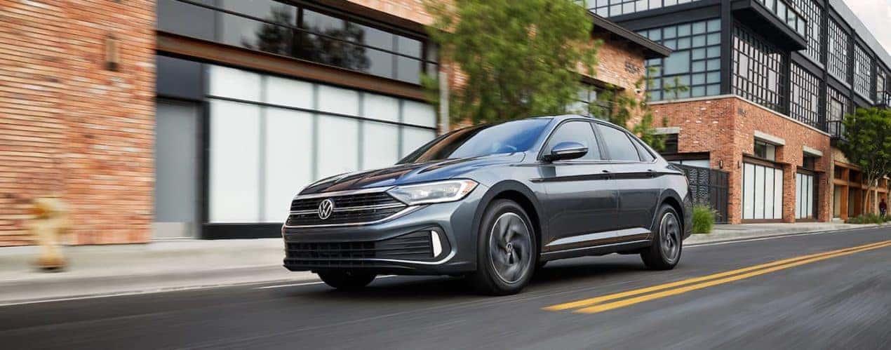 A grey 2022 Volkswagen Jetta SEL is shown from the side driving through a city.