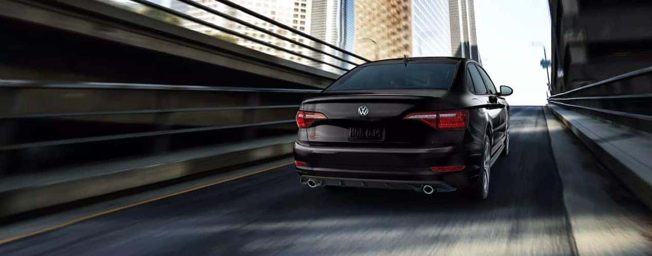 A black 2022 Volkswagen Jetta GLI is shown from the rear driving on a highway ramp.