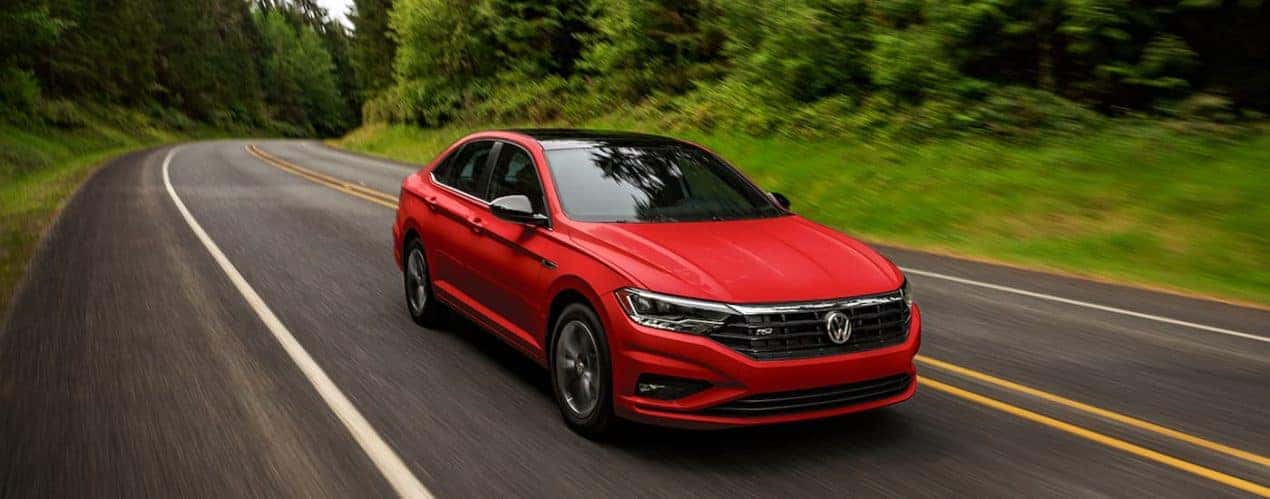 A red 2022 Volkswagen Jetta is shown driving down an open road during a 2022 Volkswagen Jetta vs 2022 Hyundai Elantra comparison.