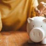 A person is shown putting money into a piggybank.