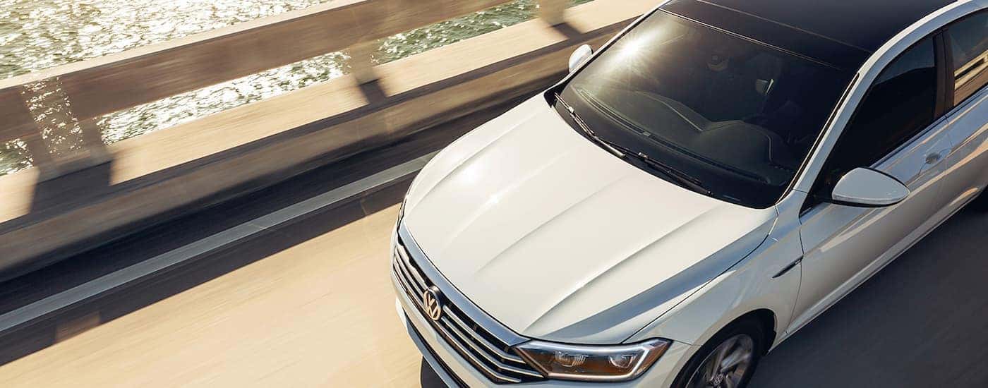 A white 2022 Volkswagen Jetta is shown driving on a bridge after viewing used Volkswagens for sale.