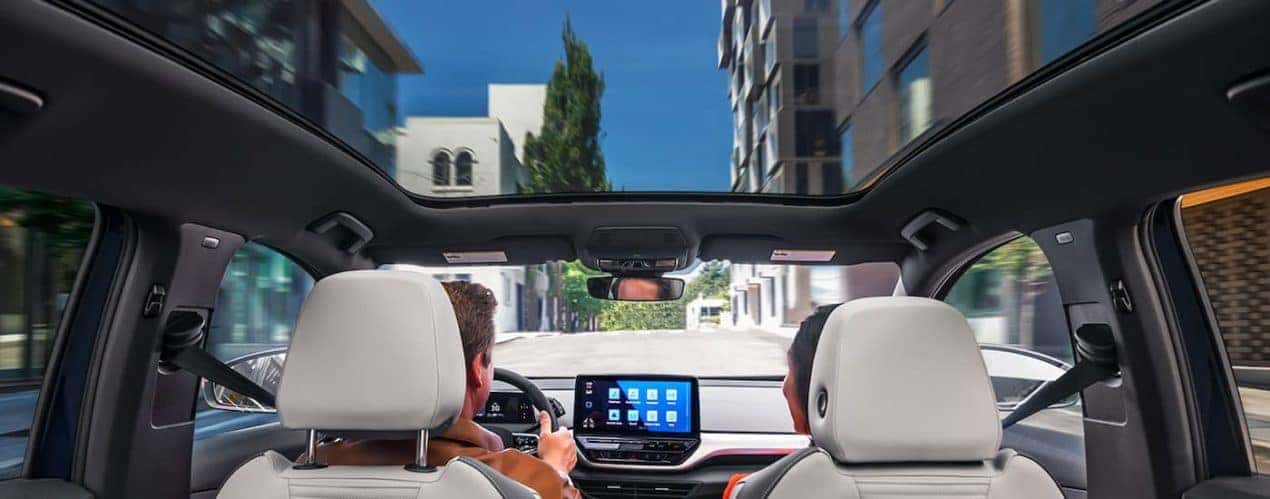A couple is shown driving in a 2022 Volkswagen ID.4 Electric Vehicle in a city.