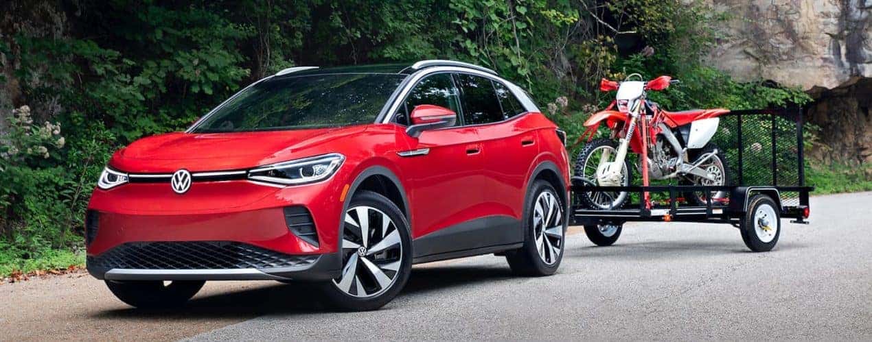 A red 2022 Volkswagen ID.4 Electric Vehicle is shown towing a dirtbike.