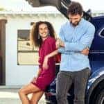 A couple is shown leaning up against a blue 2021 Volkswagen Tiguan.
