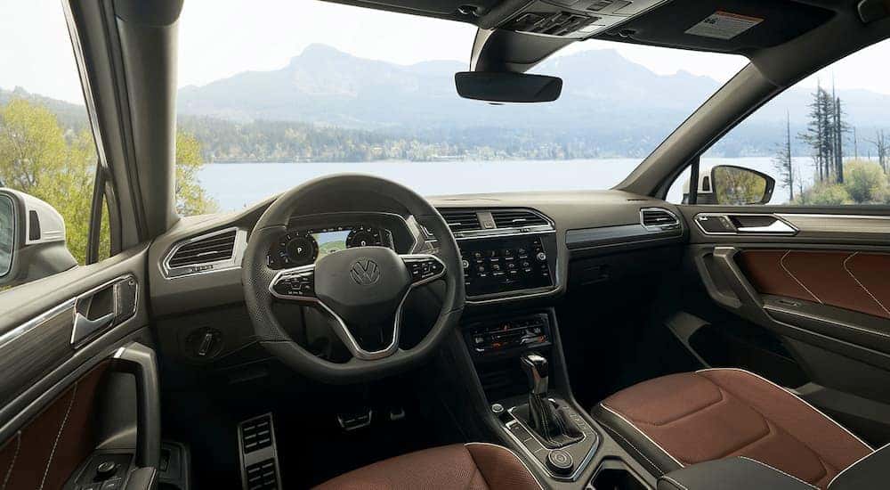 The black and brown interior of a 2022 Volkswagen Tiguan shows the steering wheel.
