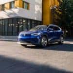 A blue 2023 Volkswagen ID.4 is shown driving on a city street.