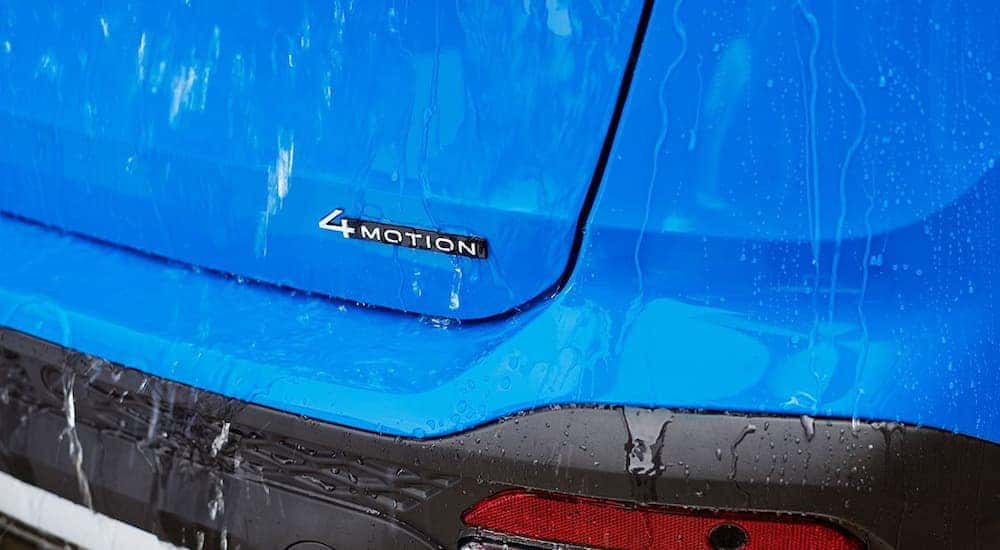 The 4Motion badge is shown on wet trunk of a blue 2023 Volkswagen Taos.