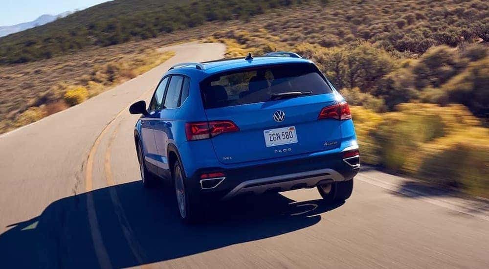 A blue 2023 Volkswagen Taos SEL is shown from the rear while driving.