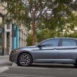 A grey 2023 Volkswagen Jetta SEL is shown from the side parked on a city street after looking at a VW Jetta for sale.