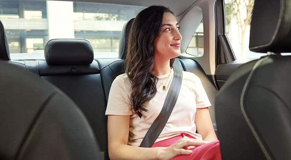The grey interior of a 2023 Volkswagen Jetta SEL shows a person sitting in the back seat.