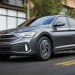 A grey 2023 Volkswagen Jetta SEL is shown driving through a city.