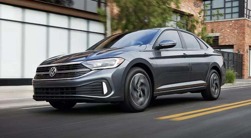 A grey 2023 Volkswagen Jetta SEL is shown driving through a city.