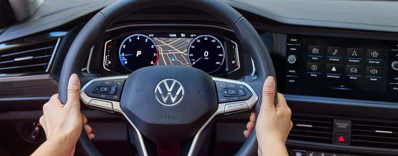 A person is shown holding the steering wheel in a 2023 Volkswagen Jetta.