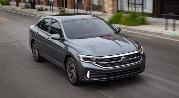 A grey 2023 Volkswagen Jetta SEL is shown driving on a city street after viewing a VW Jetta for sale.
