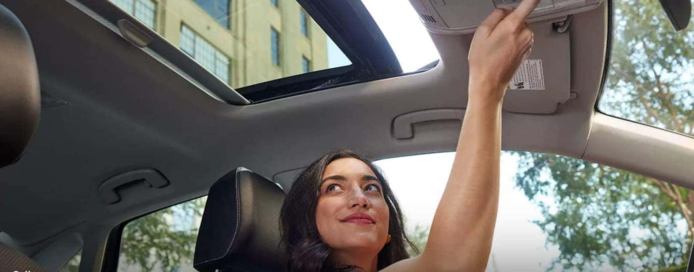 A woman is shown opening the sunroof in a 2023 Volkswagen Jetta.