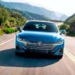 A blue 2023 Volkswagen Arteon is shown driving on an open road.