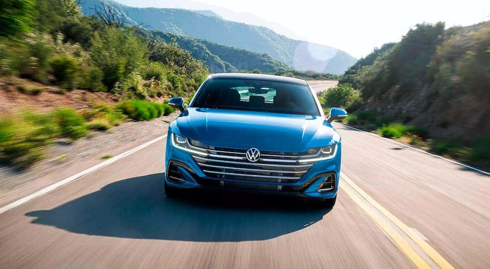 A blue 2023 Volkswagen Arteon is shown driving on an open road.