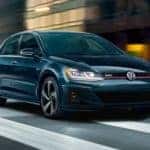 A black 2020 Volkswagen Golf GTI is shown driving on a city street.