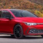 A red 2023 Volkswagen Golf GTI 40th Anniversary Edition is shown parked with a mountain view.