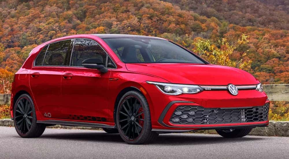 A red 2023 Volkswagen Golf GTI 40th Anniversary Edition is shown parked with a mountain view.
