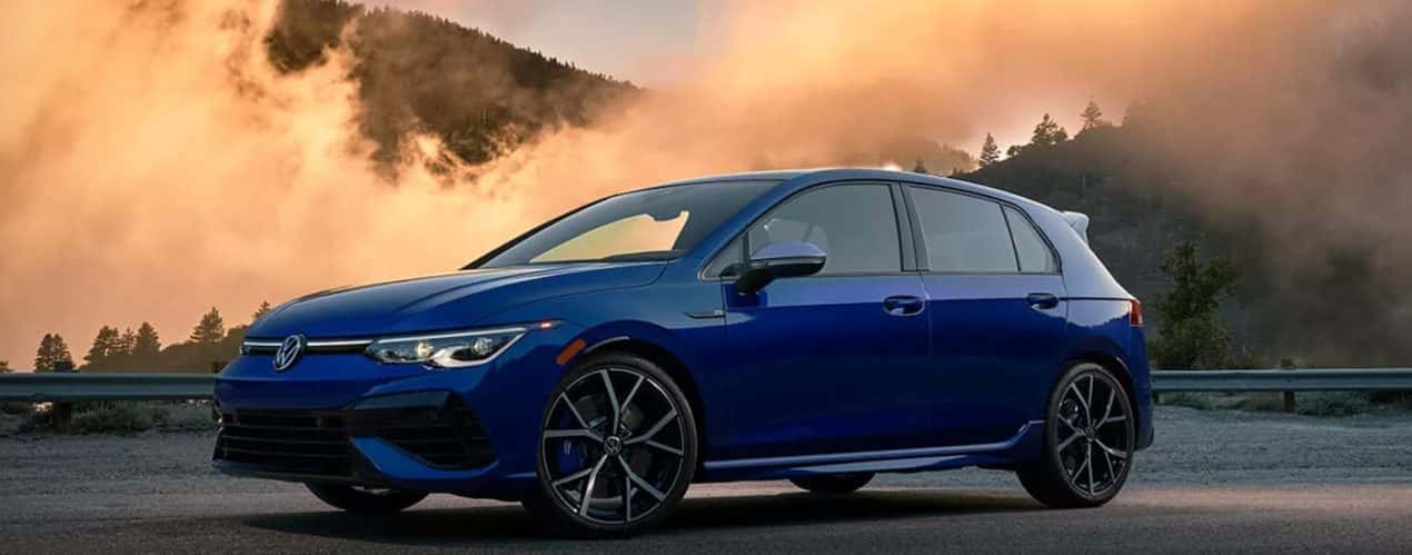 A blue 2023 Volkswagen Golf R is shown parked in an empty lot.