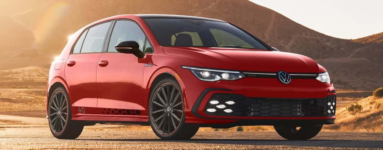 A red 2023 Volkswagen Golf GTI 40th Anniversary is shown parked with a mountain view.