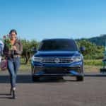 A blue 2023 Volkswagen Tiguan for sale is shown parked at a flower shop.