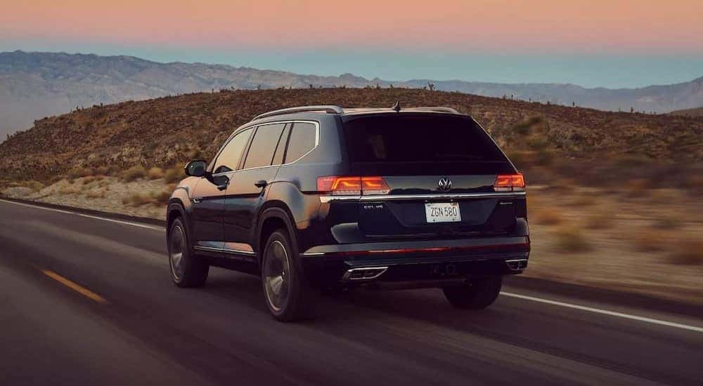 A black 2023 Volkswagen Atlas is shown from the rear driving on a highway.