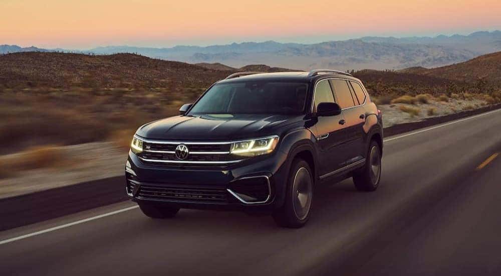 A black 2023 Volkswagen Atlas is shown driving on a highway.