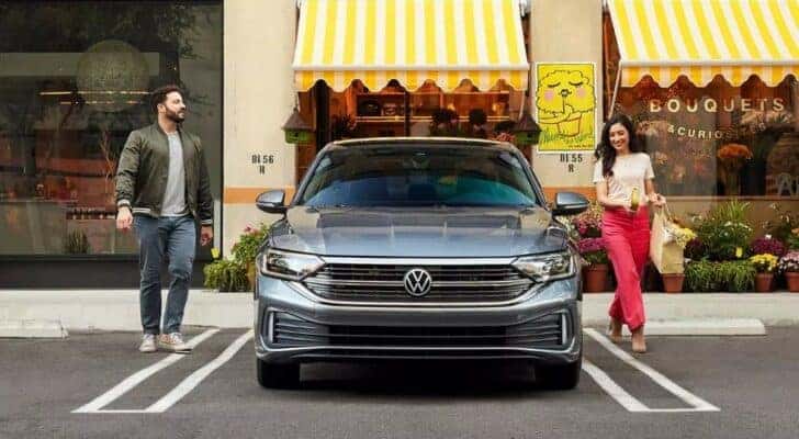 A popular vehicle for VW lease deals, a grey 2023 Volkswagen Jetta, is shown in front of a flower shop.