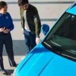 A sales associate and a customer look at a blue Volkswagen SUV