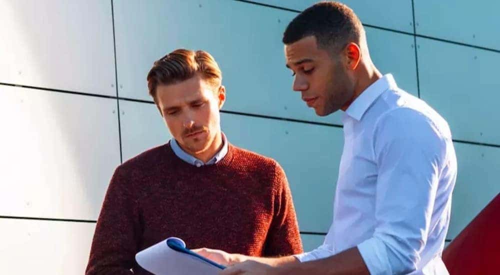 A dealership employee is shown assisting a customer with financial services.