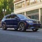 A blue 2023 Volkswagen Tiguan R-Line is shown driving on a city street.